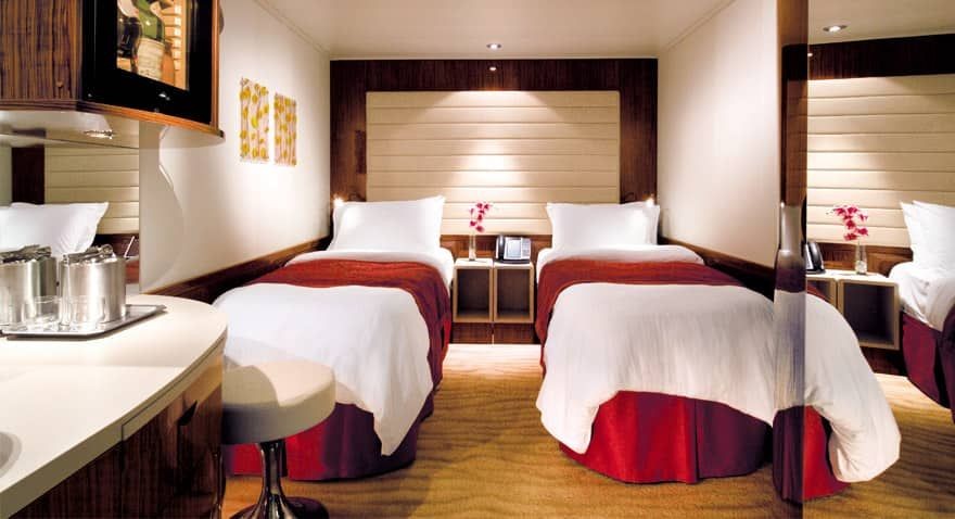 Luxurious hotel room with two twin beds, a vanity area, and modern decor.