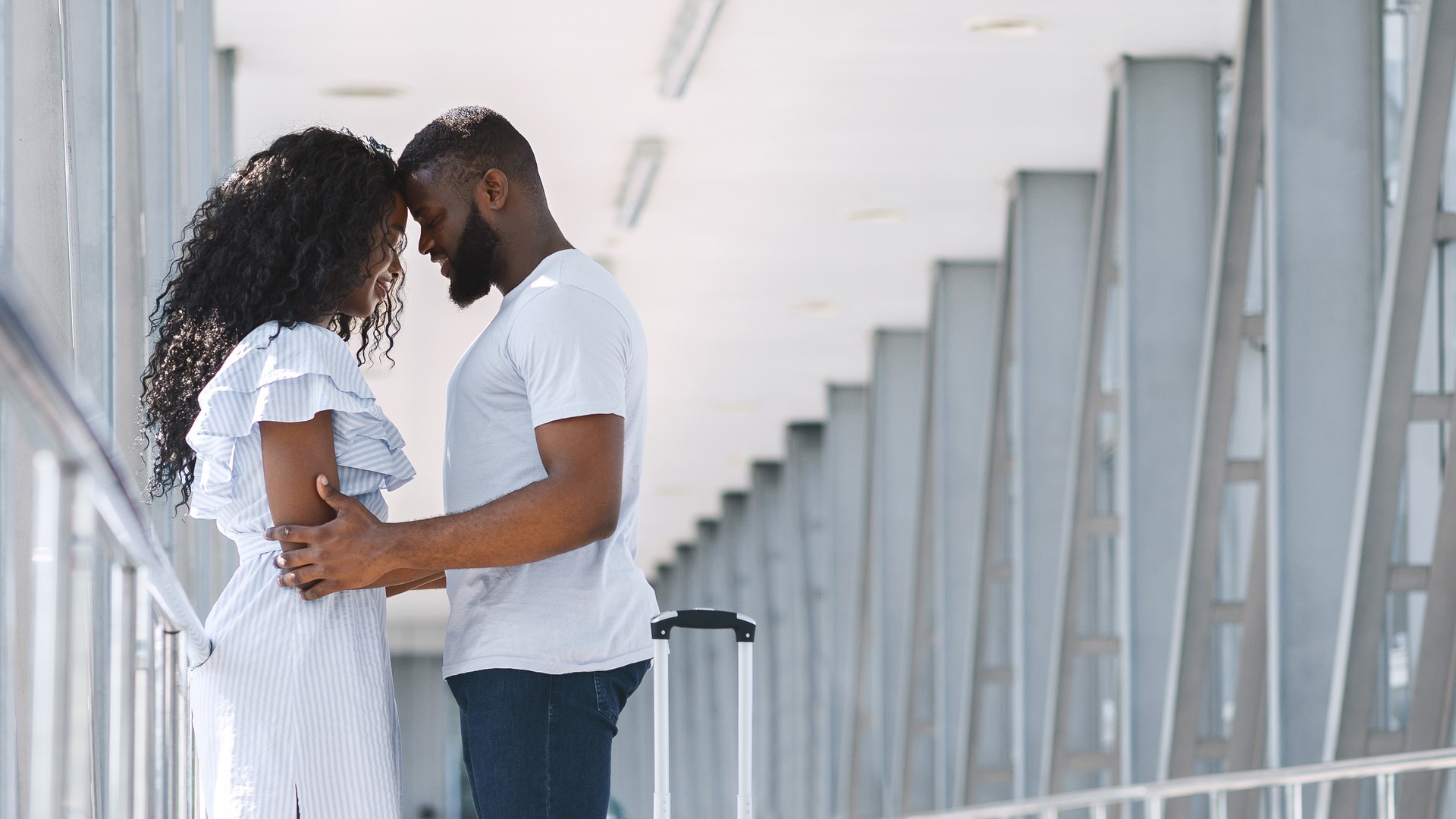 African american couple cuddling at airport before flight departure