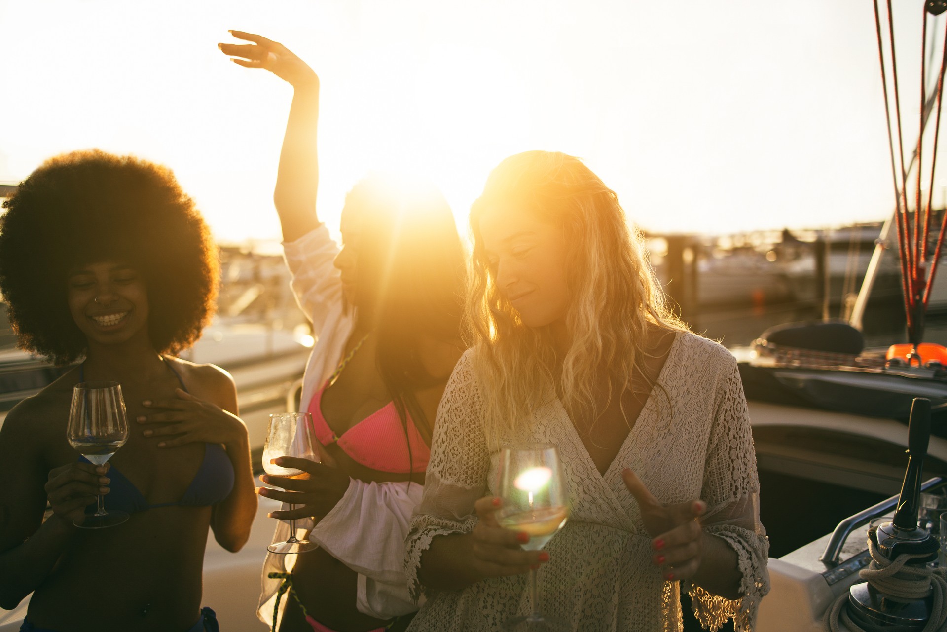 Young female friends having fun dancing together in sailing boat party - Soft focus on right girl face